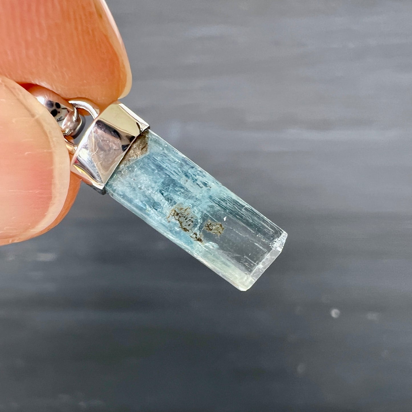 Detailaufnahme eines rohen Aquamarin Kristalls mit sichtbaren Einschlüssen und Silberfassung | Happy Minerals