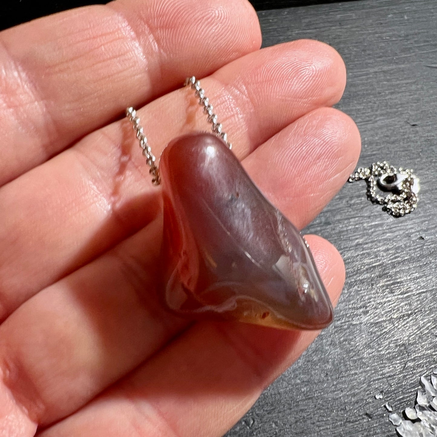 Seltener Swazi Achat Anhänger, gebohrt ca. 34mm. Mit Silberkette, in der Håand. | Happy Minerals