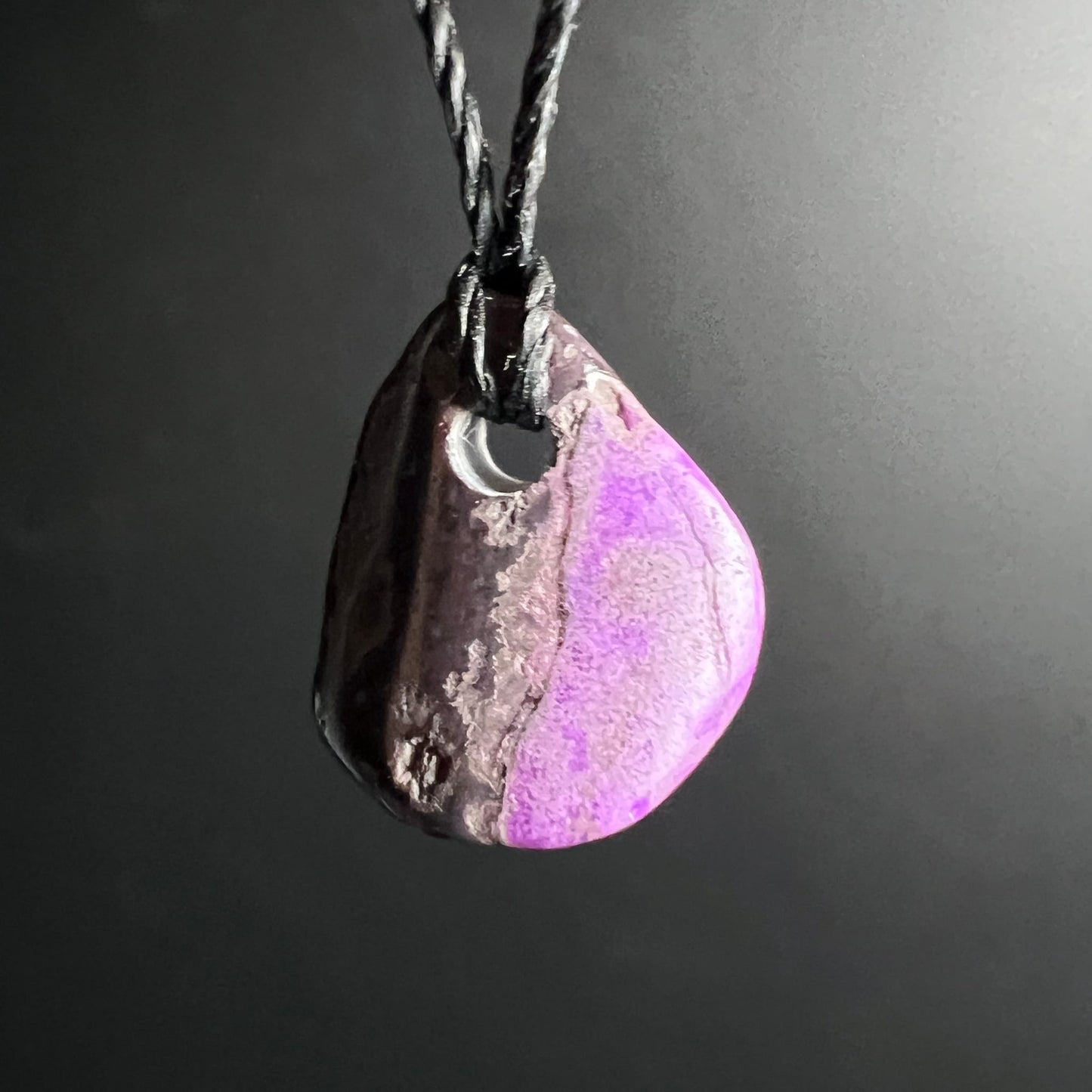 Sugilith Anhaenger tropfenfoermig, dunkelbraun mit violett-rosa gesprenkelter Zone, gedrehte Kordel | Happy Minerals