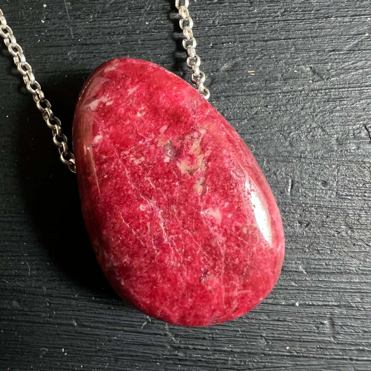 Thulit Tropfen | kräftiges Pink-Rot | feine Musterung | auf dunklem Holz | Happy Minerals Unikat