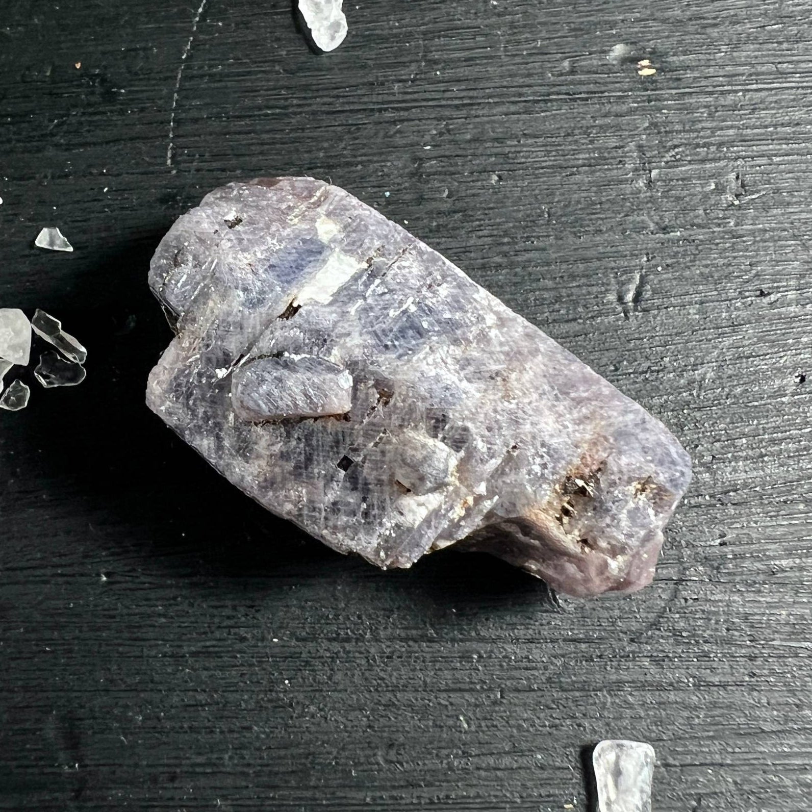 Rosa-blauer Saphir Rohstein auf dunklem Holz | schimmernde Kristallflächen | Happy Minerals