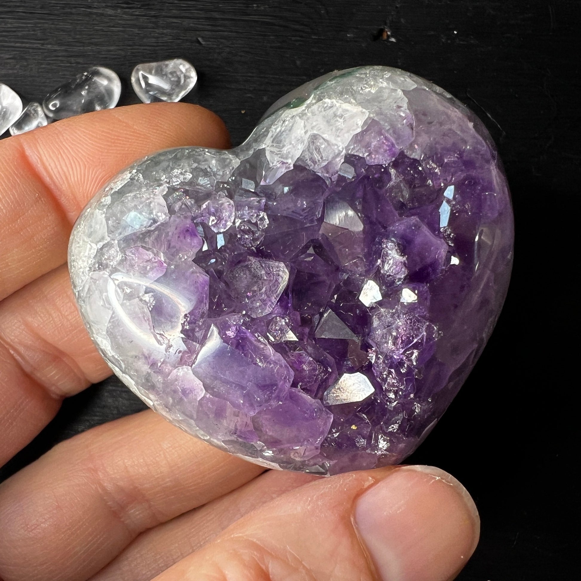 Das Amethystherz ist poliert und liegt sanft in der Hand. Die Unterseite ist teilpoliert.  Größe: 53x49mm. In der Hand. | Happy Minerals