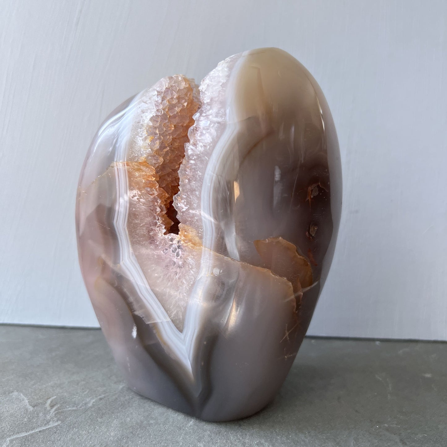 Foto mit hellem HIntergrund der glitzernden Amethyst-Druse mit goldorangefarbenem Limonit im Inneren | Happy Minerals
