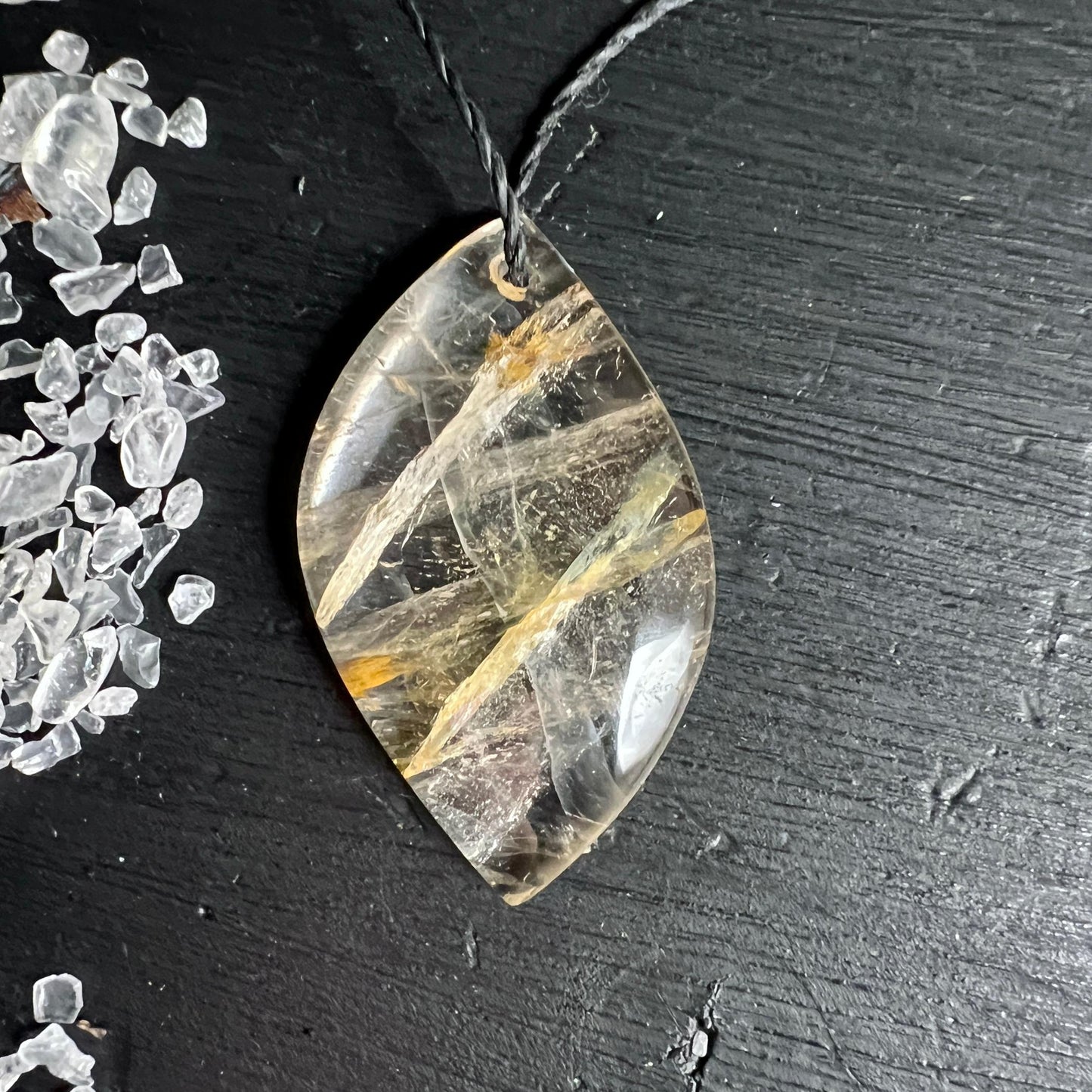 Golden Healer Quarz Anhänger mit goldenen Limonit-Einschlüssen auf dunklem Holz | Happy Minerals