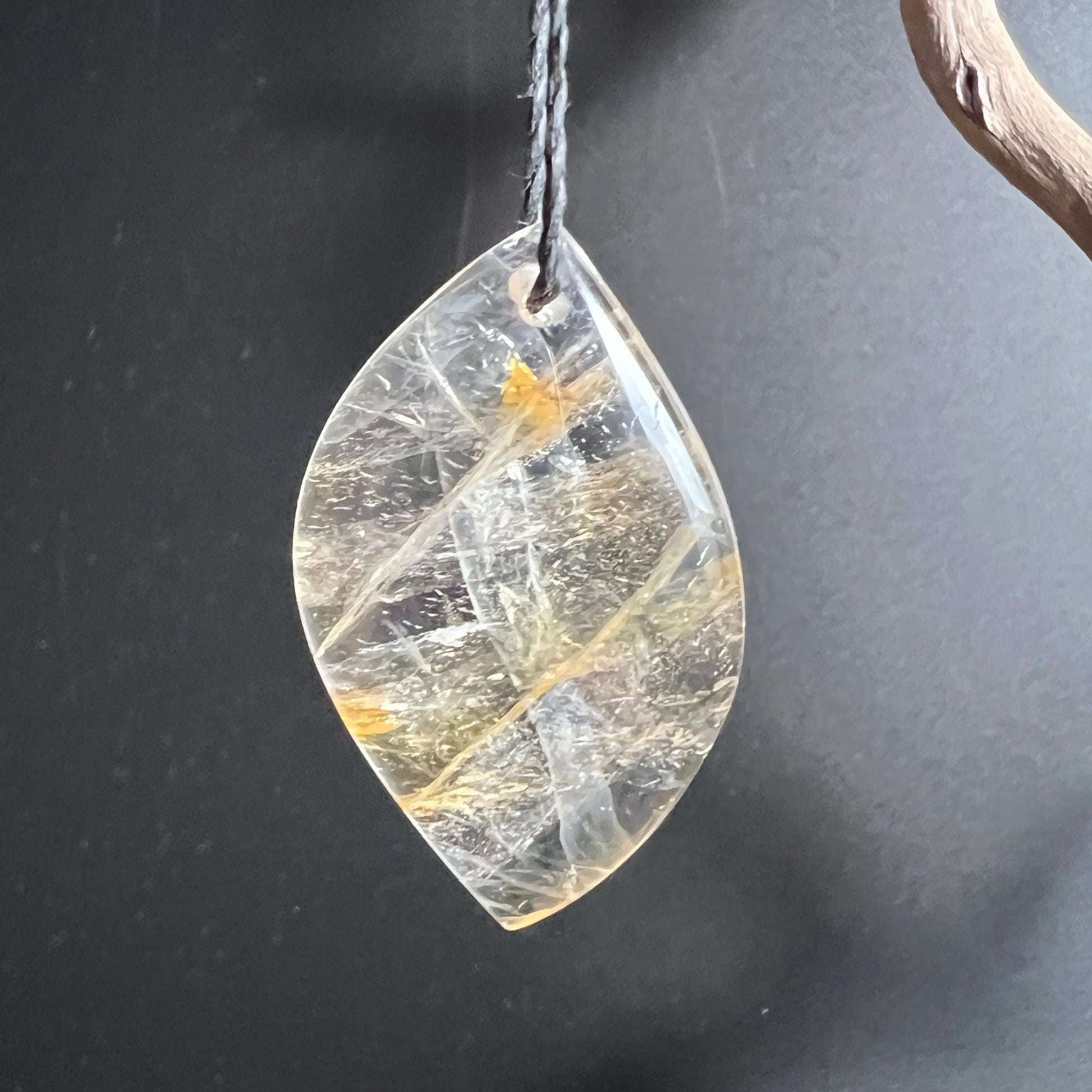 Golden Healer Quarz Anhänger hängend am schwarzen Band mit Lichtreflexen | Happy Minerals