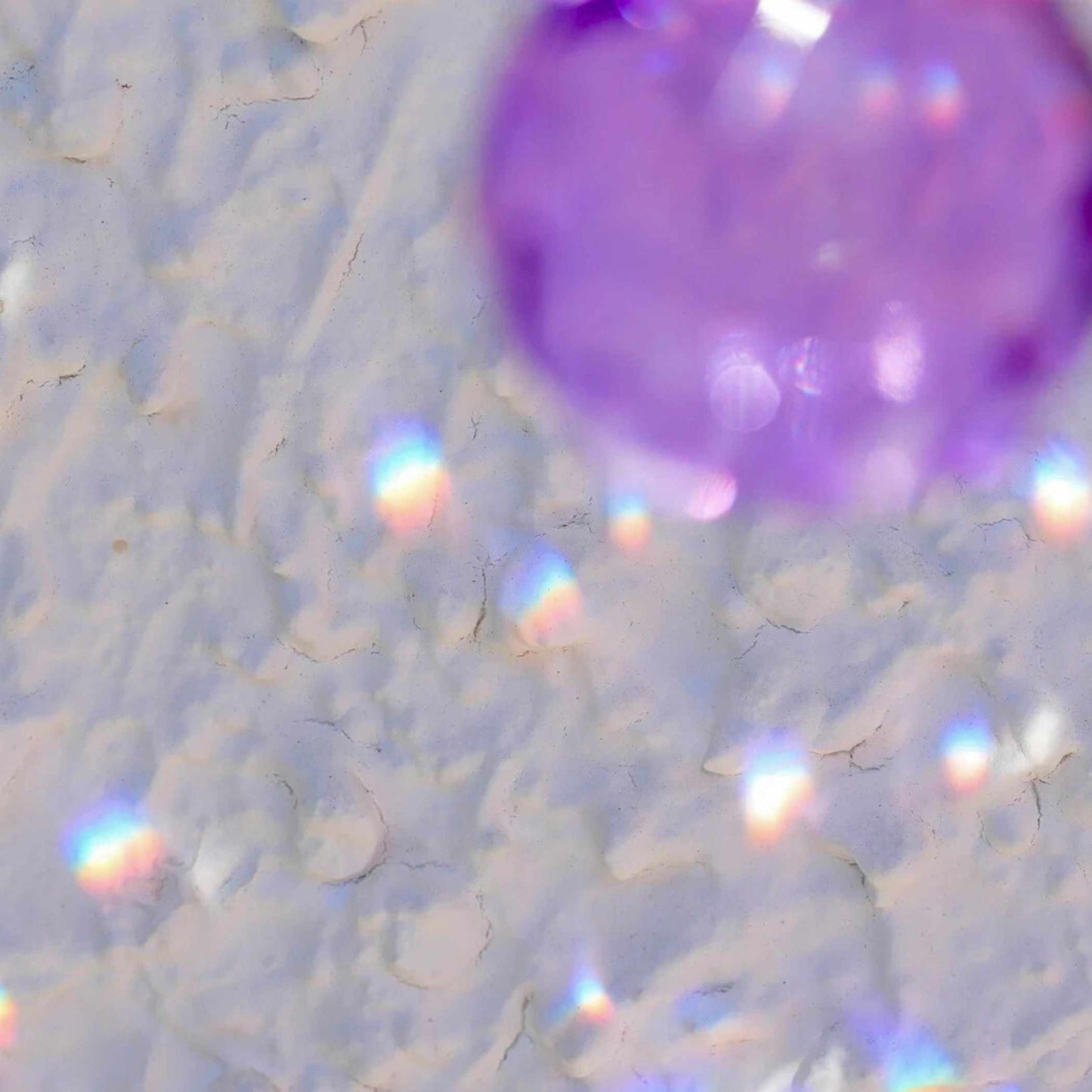 Lila Kristall-Sonnenfänger hängt im Fenster und wirft violette Lichtreflexe | Happy Minerals