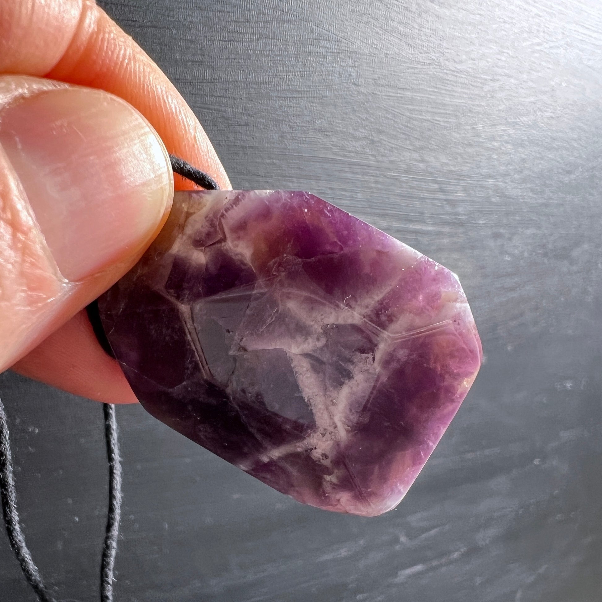Lila-weißer Dream Amethyst Anhänger, Polygon Form, im Licht.  | Happy Minerals