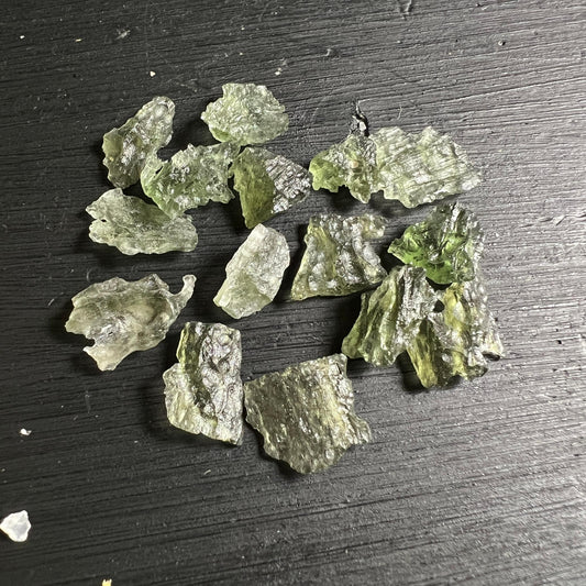 Sammlung kleiner Besednice Moldavite auf dunklem Holz grün glasig | Happy Minerals