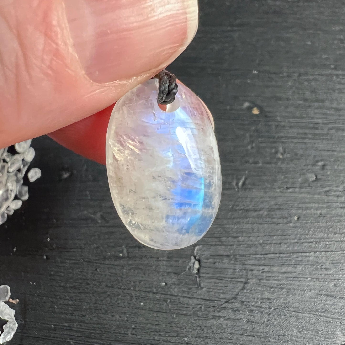 Regenbogen Mondstein Anhänger in der Hand mit leuchtendem blauen Schimmer | Happy Minerals