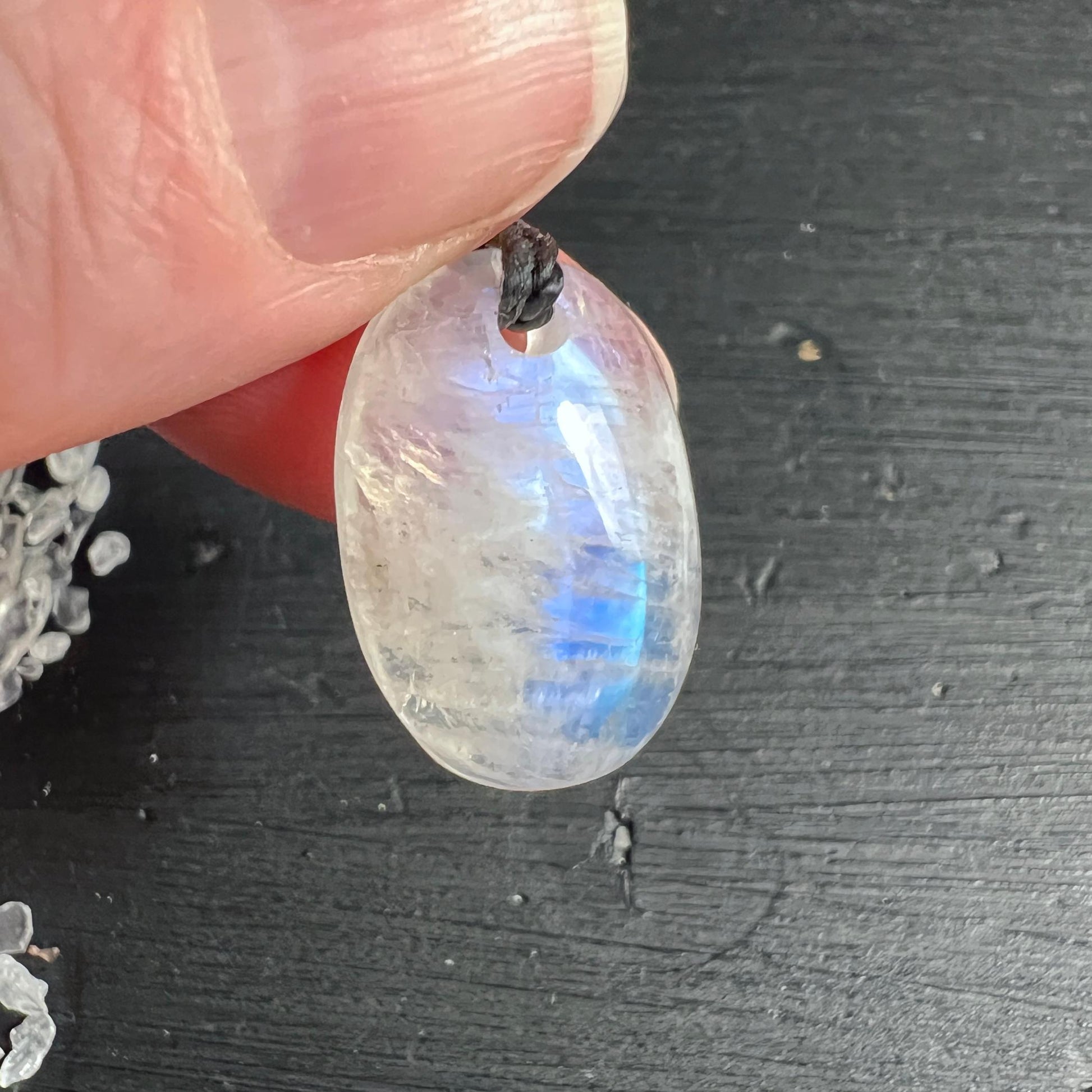 Regenbogen Mondstein Anhänger in der Hand mit leuchtendem blauen Schimmer | Happy Minerals