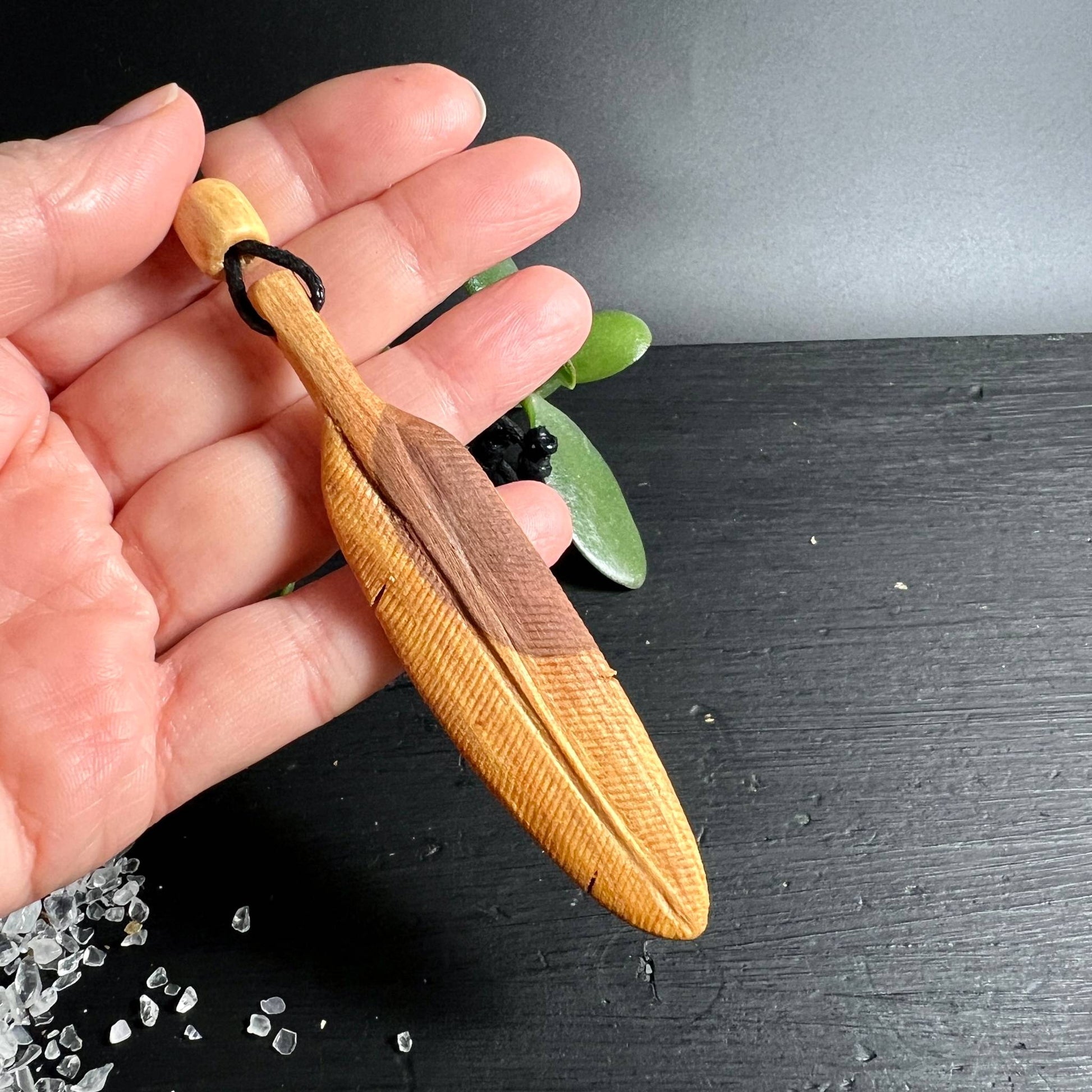 Palo Santo Feder Anhänger in der Hand | handgeschnitzte Rillenstruktur Honigfarben | Happy Minerals
