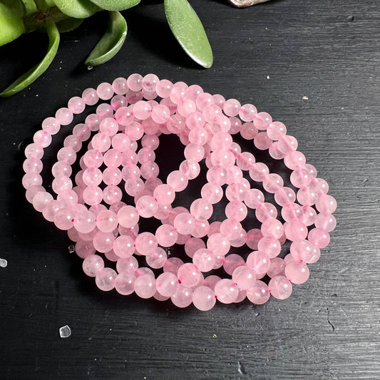Rosenquarz Armbänder 6mm rosa Perlen gestapelt auf dunklem Grund | Herzchakra Schmuck | Happy Minerals