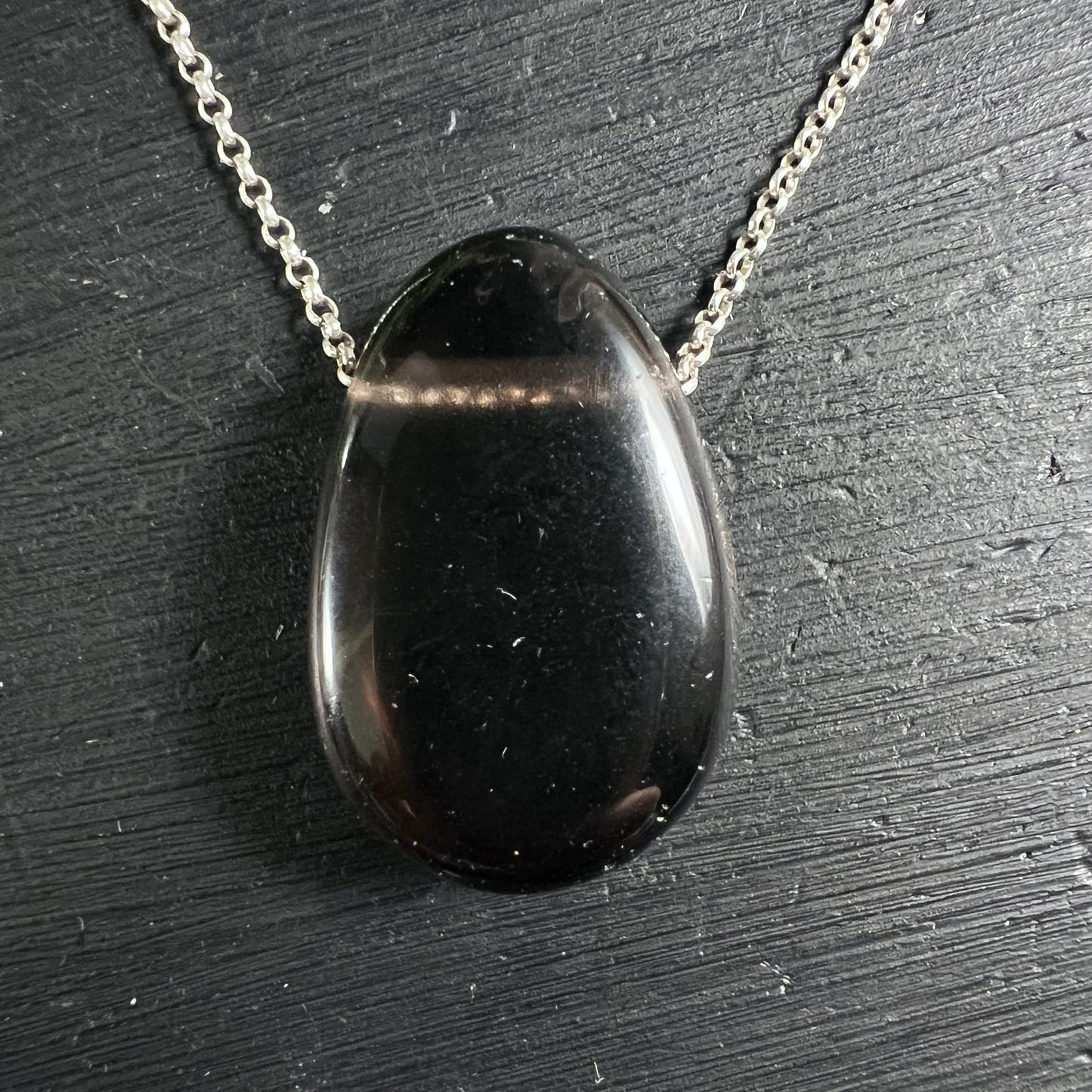 Apachenträne Mexico | tiefschwarz glänzend | ovaler Cabochon | Silberkette | schwarzer Untergrund | Happy Minerals