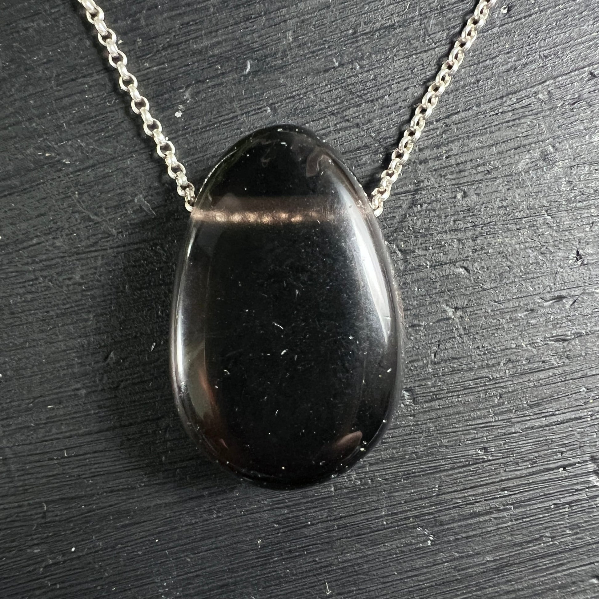 Apachenträne Mexico | tiefschwarz glänzend | ovaler Cabochon | Silberkette | schwarzer Untergrund | Happy Minerals