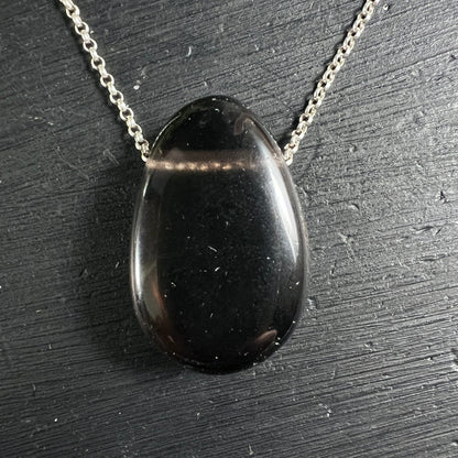 Apachenträne Mexico | tiefschwarz glänzend | ovaler Cabochon | Silberkette | schwarzer Untergrund | Happy Minerals