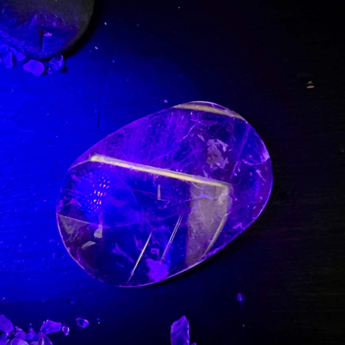 Bergkristall Handschmeichler oval-poliert, violett fluoreszierend, mit gelbem Fluorit-Einschluss als leuchtende Linie unter UV | Happy Minerals