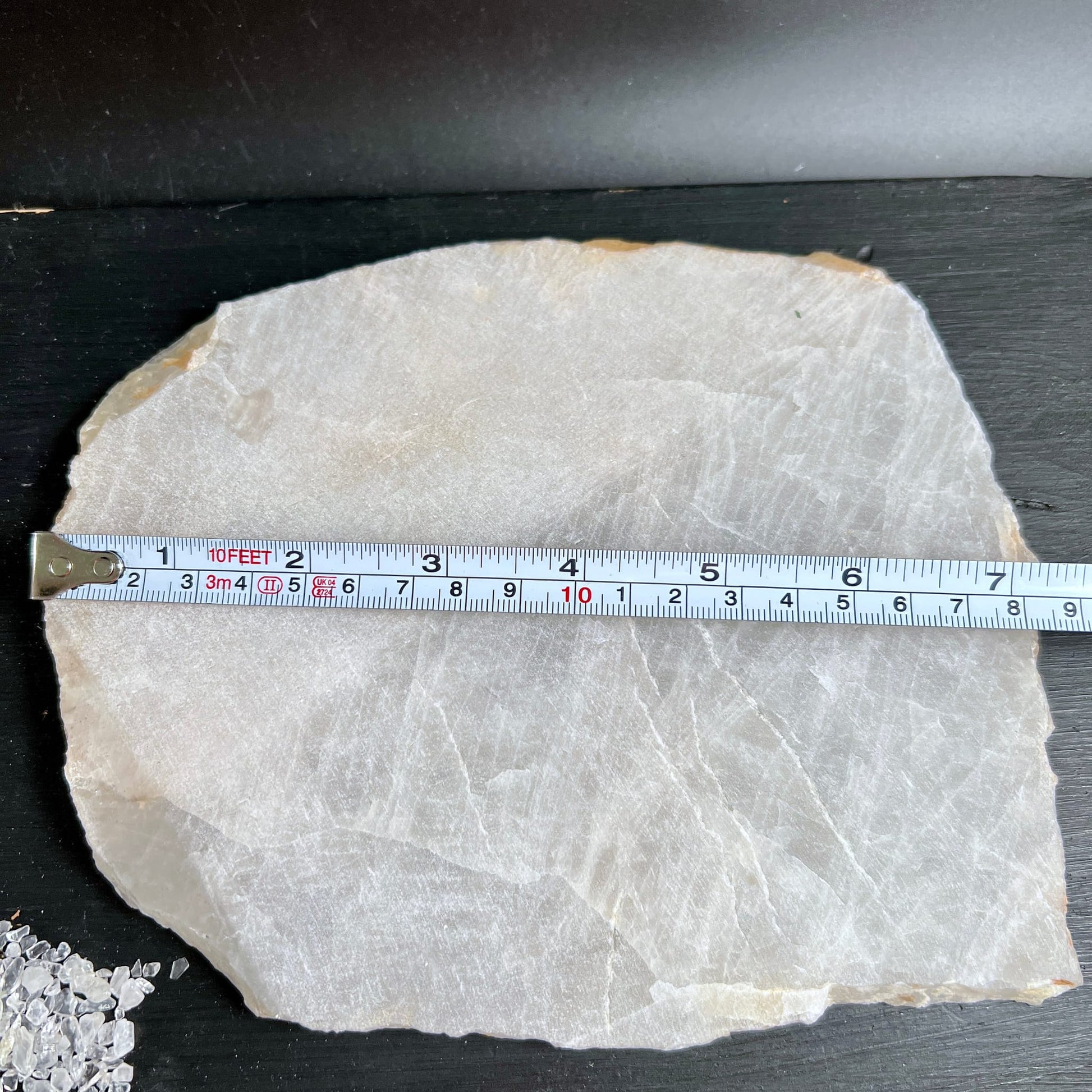 Rohe Bergkristall Platte cremig-weiss mit feinen Rissen, flache unregelmaessige Form, Massband zeigt Groesse | Happy Minerals