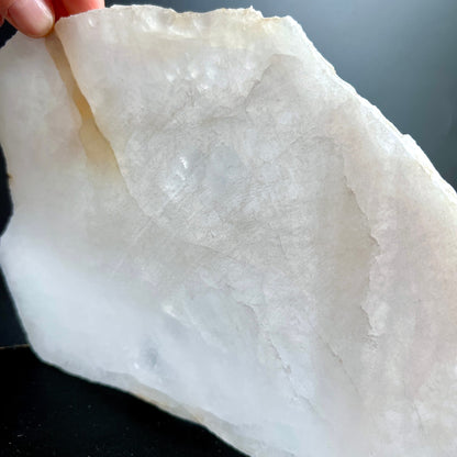 Bergkristall Platte milchig-weiss mit grauen Wolken, rohe gezackte Kante, in Hand gehalten | Happy Minerals