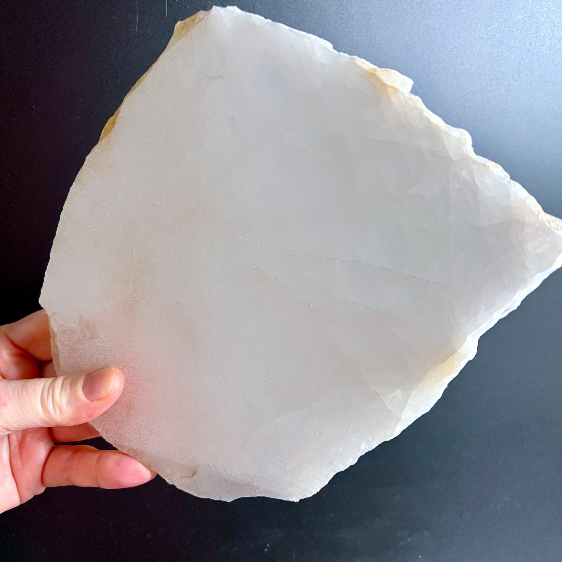 Bergkristall Platte milchig-weiss mit rauer Bruchkante und goldbraunen Rändern, in Hand gehalten | Happy Minerals