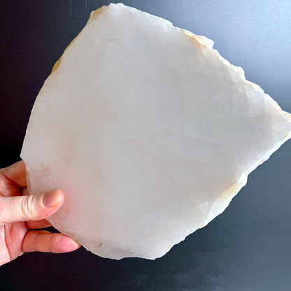 Bergkristall Platte milchig-weiss mit rauer Bruchkante und goldbraunen Rändern, in Hand gehalten | Happy Minerals