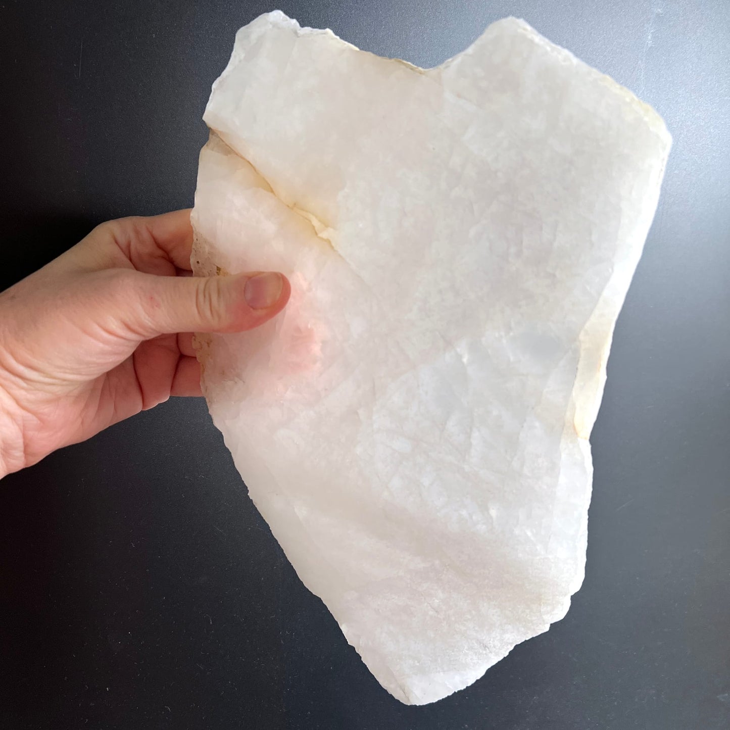 Bergkristall Platte milchig-weiss mit rauen Bruchkanten, poliert gehalten in Hand | Happy Minerals
