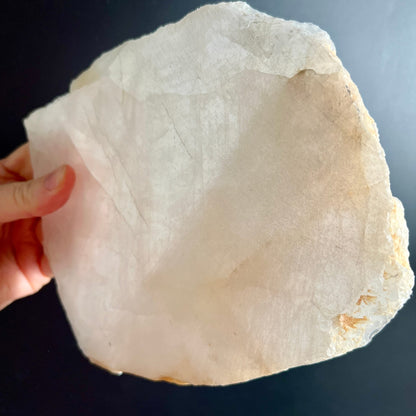 Bergkristall Platte roh mit milchig-weisser Flaeche und leicht gelblichen Raendern, in Hand gehalten | Happy Minerals