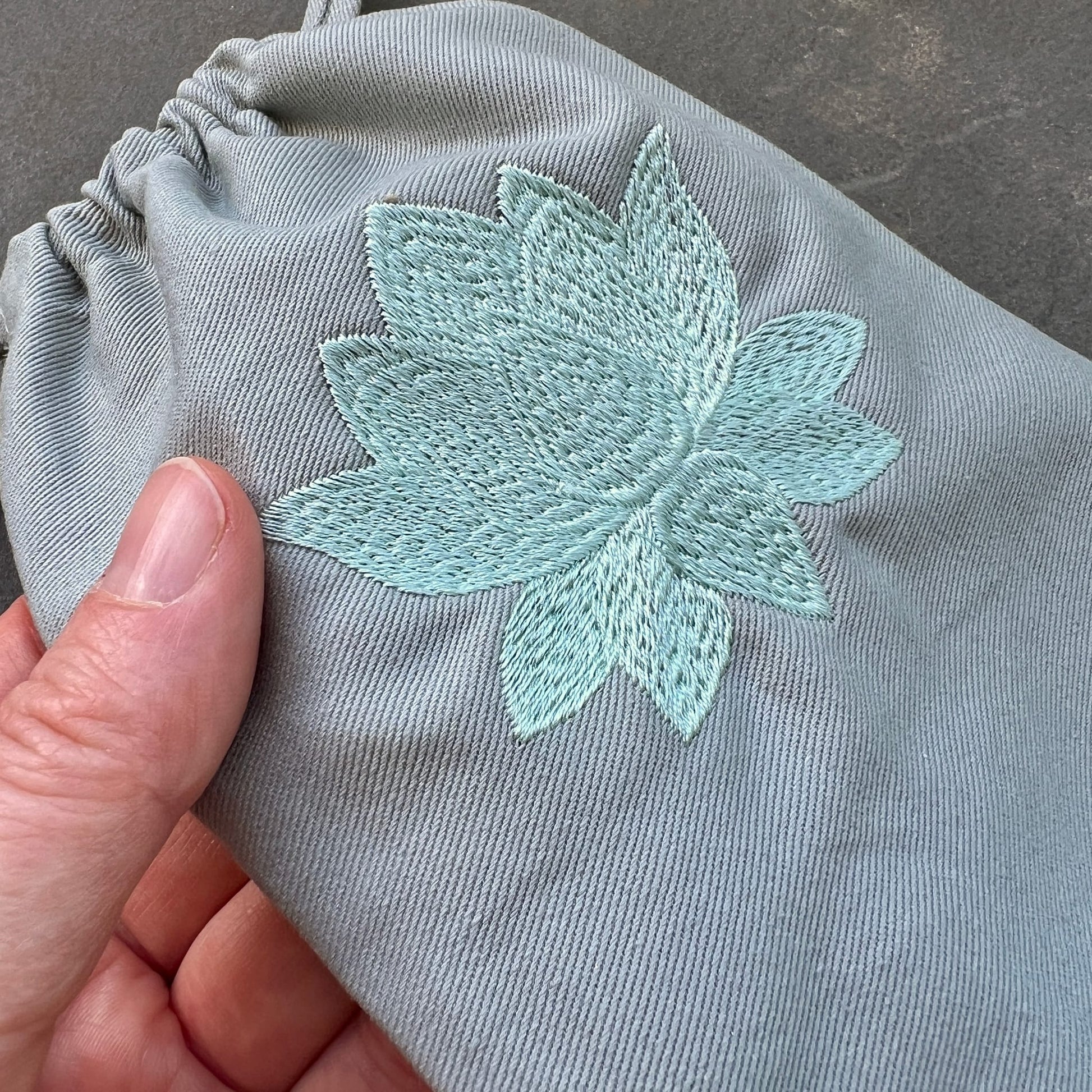 Mintgrüner Bio-Stoffbeutel mit bestickter Lotus-Blüte in hellem Türkisgrün, Zugband oben | Happy Minerals