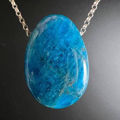 Blauer Apatit Anhänger | auf silberner Kette | leuchtend blau | dunkler Hintergrund | Happy Minerals