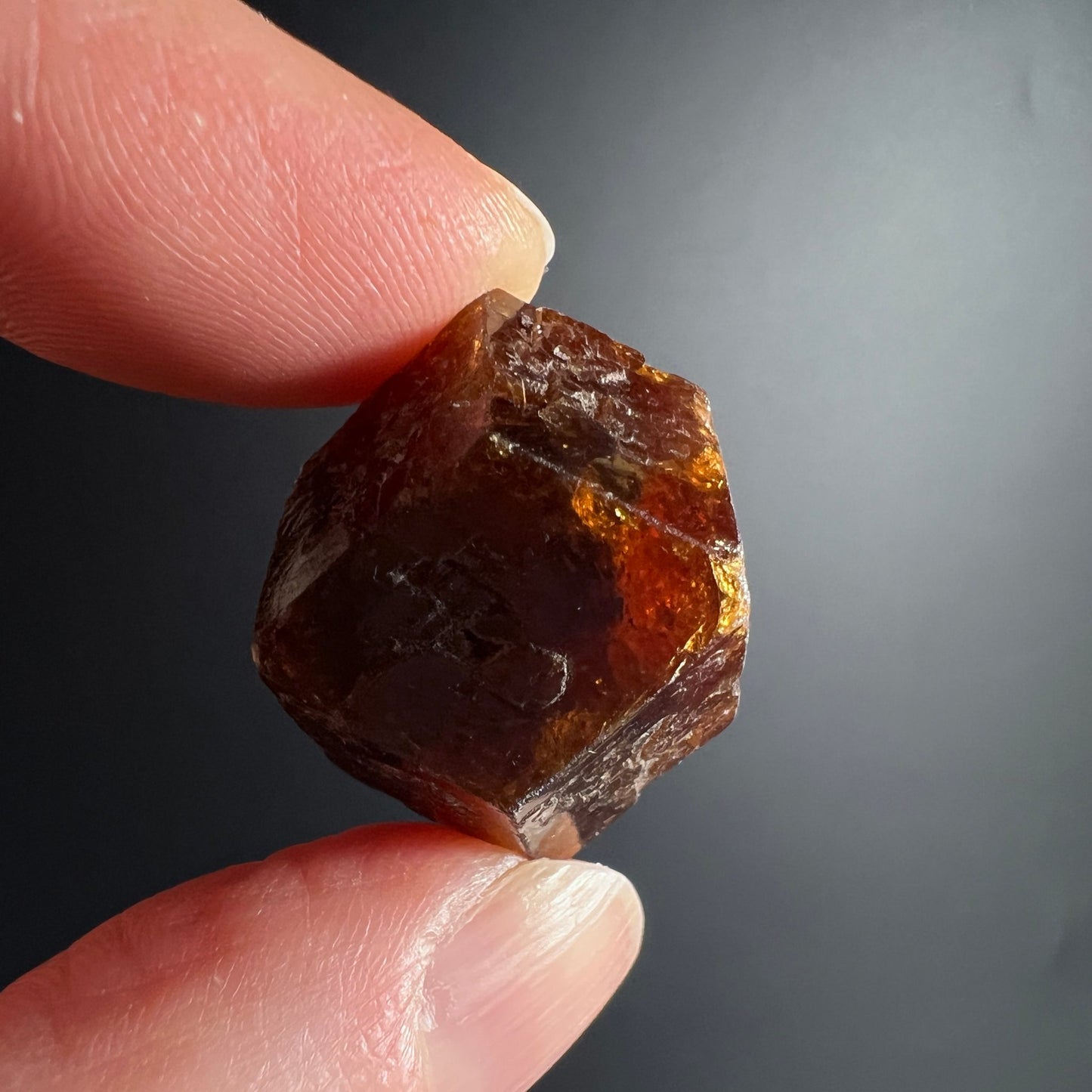 Brauner Spessartin Mali | Granat Rohstein Handhaltung | transparente Bereiche | warmes Licht | Happy Minerals