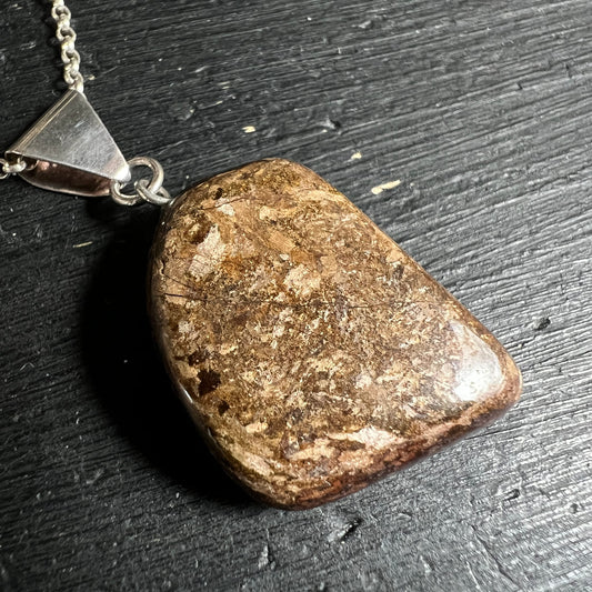 Bronzit Edelstein Anhänger | liegend auf Schiefer | erdige Brauntöne | Detailansicht | Happy Minerals