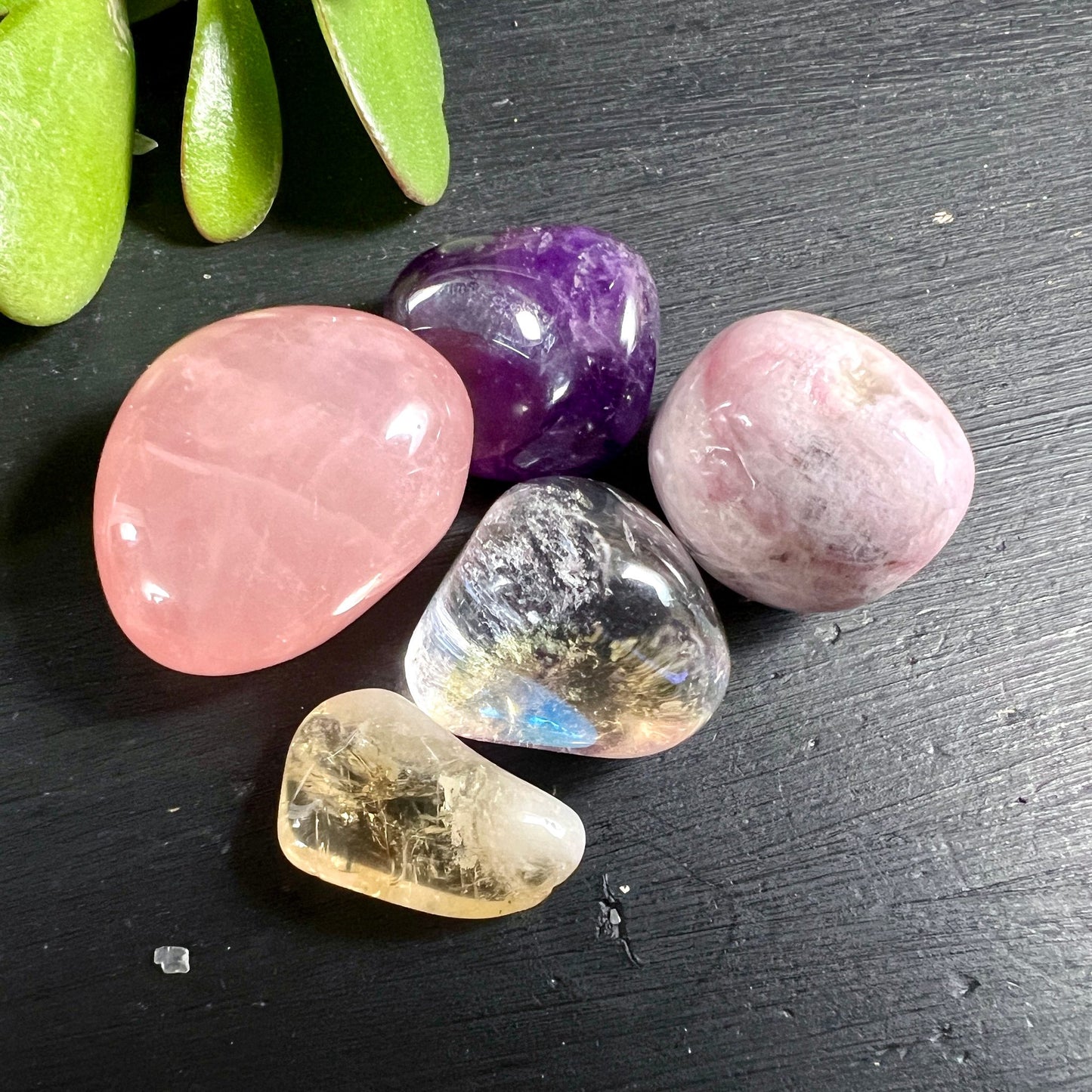 5 edle Trommelsteine rosa | violett | gelb | irisierend auf natürlichem Holzuntergrund | Happy Minerals