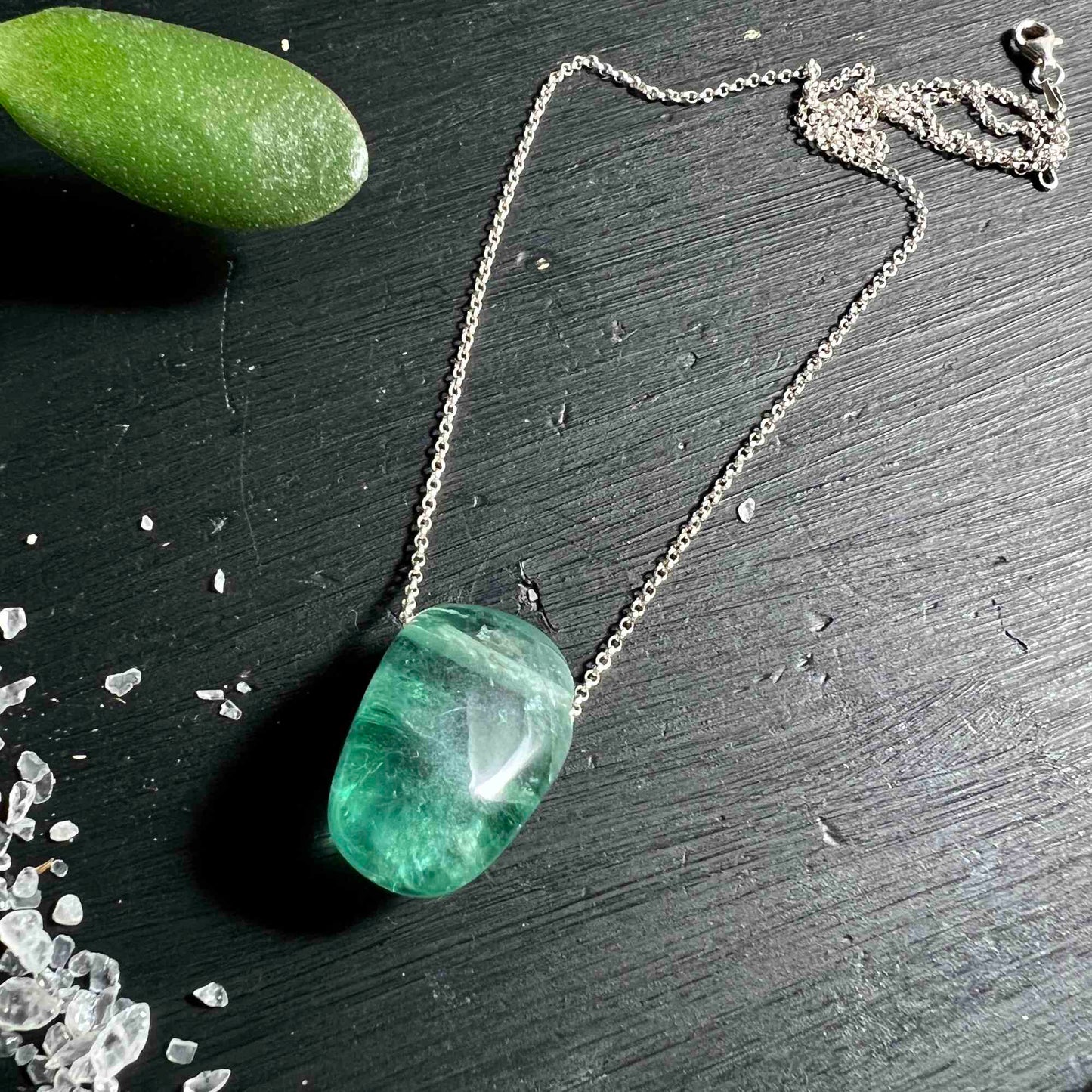 Blau grüner Fluorit Anhänger auf schwarzem Holz