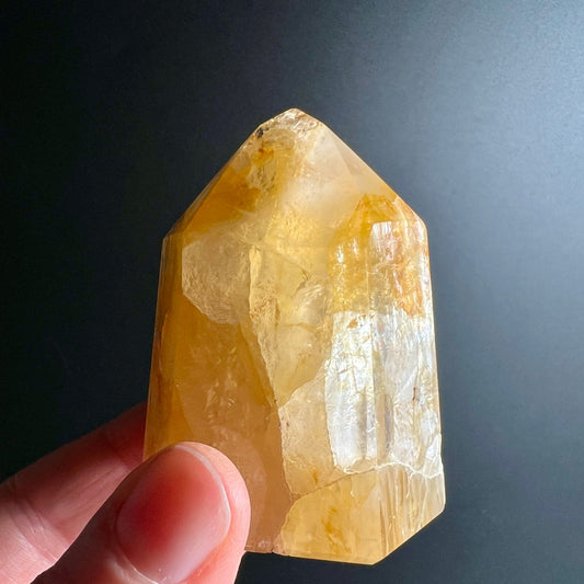 Golden Healer Quarz | Hand hält Kristall | warmes Licht | transparente Struktur | Happy Minerals