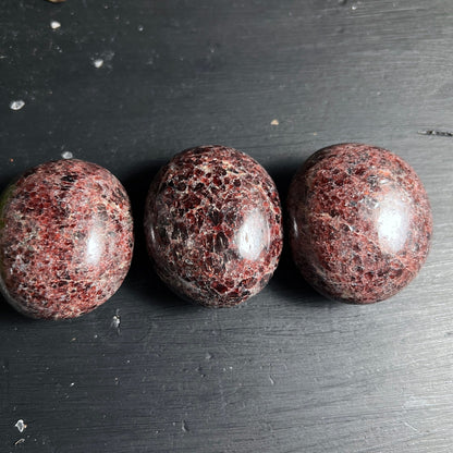 Granat Almandin Trio | polierte Steine | weinrote Kristalleinschlüsse | dunkler Holzhintergrund | Happy Minerals