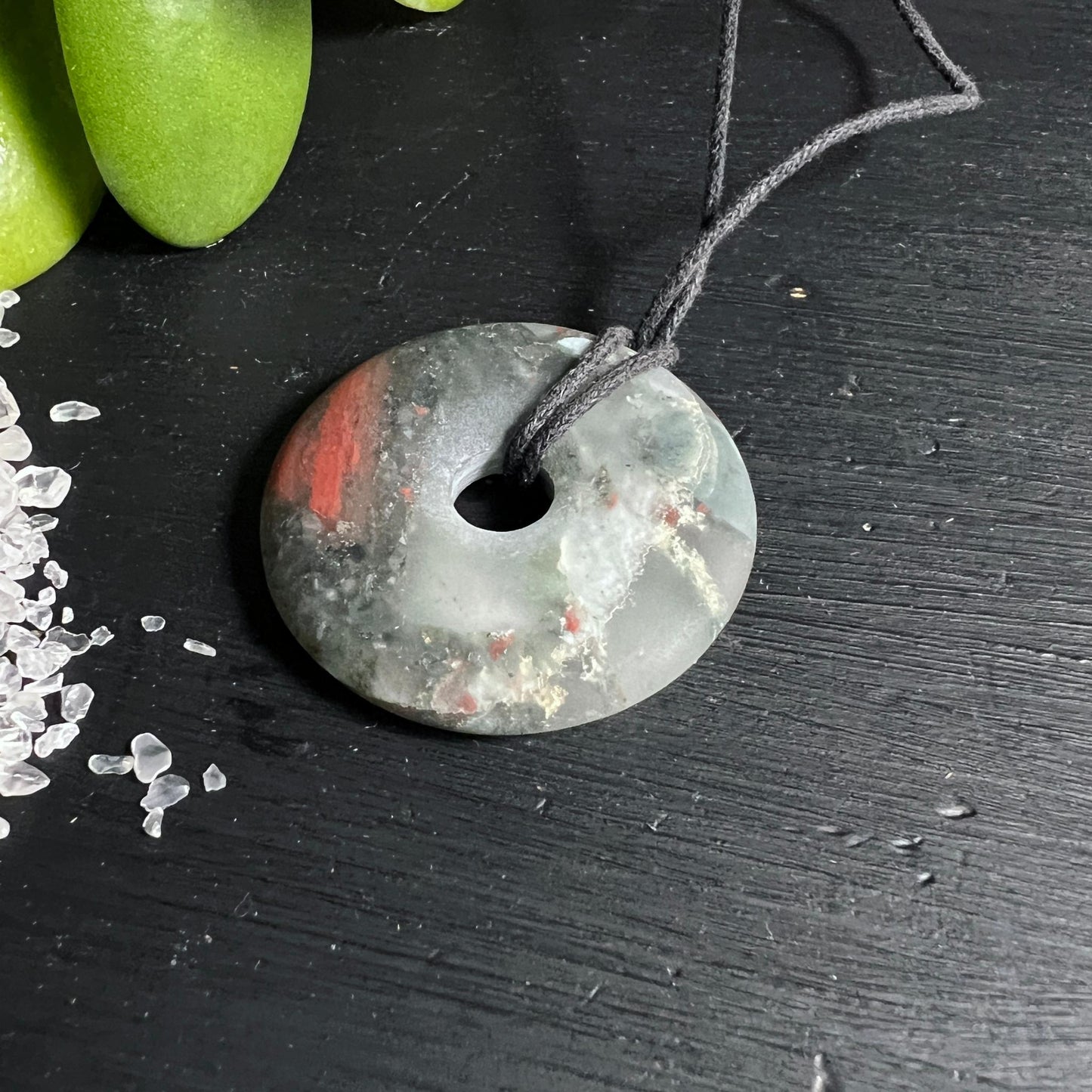 Afrikanischer Blutstein Donut mit Bergkristall Deko grüner Hintergrund