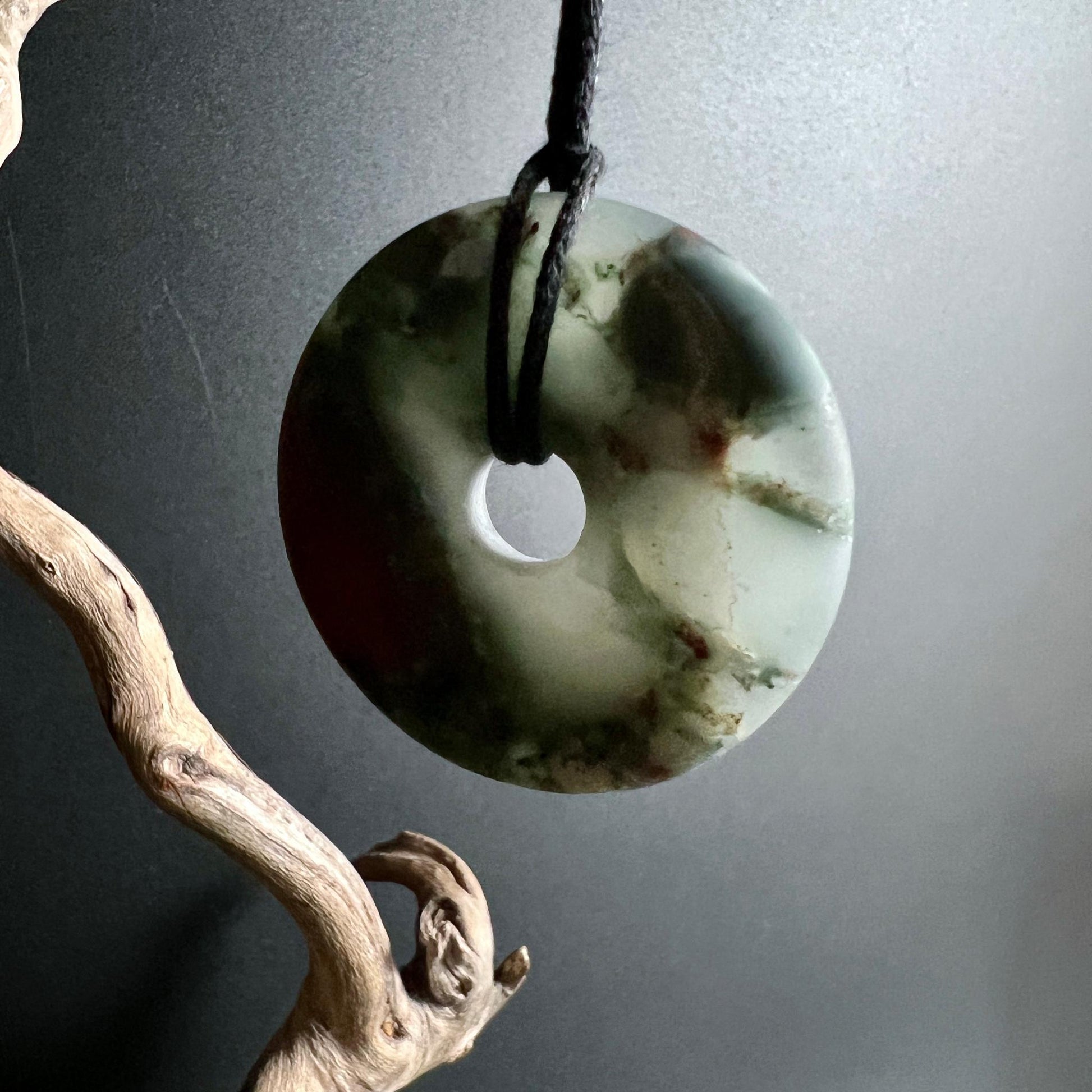 Transluzenter Heliotrop Donut am Band hängend mit Treibholz