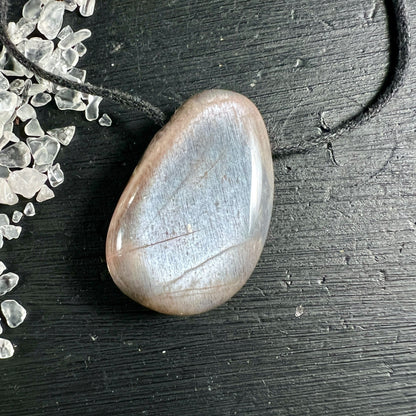 Cremefarbener Mondstein Anhänger tropfenförmig mit Schimmereffekt auf dunklem Holz | Happy Minerals