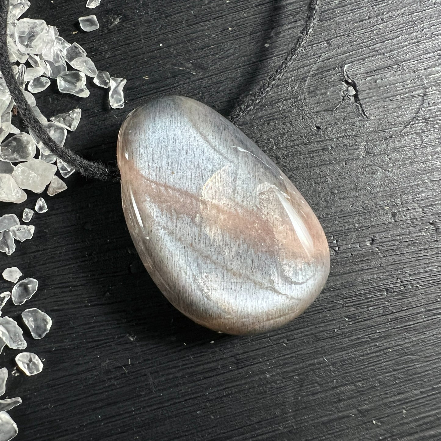 Cremefarbener Mondstein Anhänger tropfenförmig mit silbrigem Schimmer auf Holz | Happy Minerals