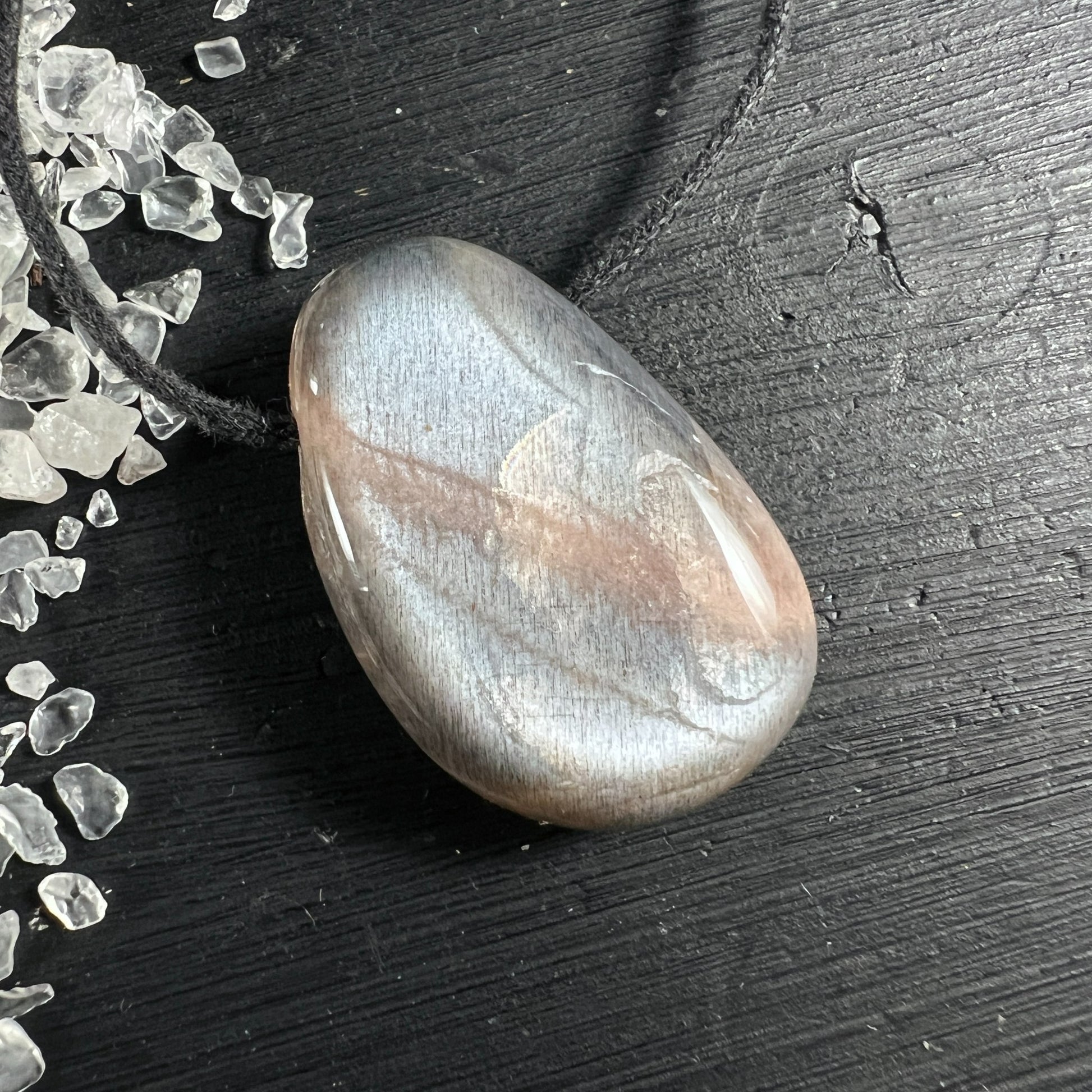 Cremefarbener Mondstein Anhänger tropfenförmig mit silbrigem Schimmer auf Holz | Happy Minerals