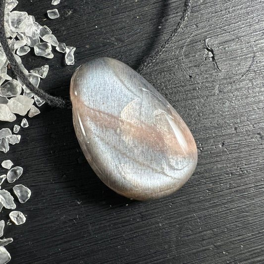 Cremefarbener Mondstein Anhänger tropfenförmig mit silbrigem Schimmer auf Holz | Happy Minerals
