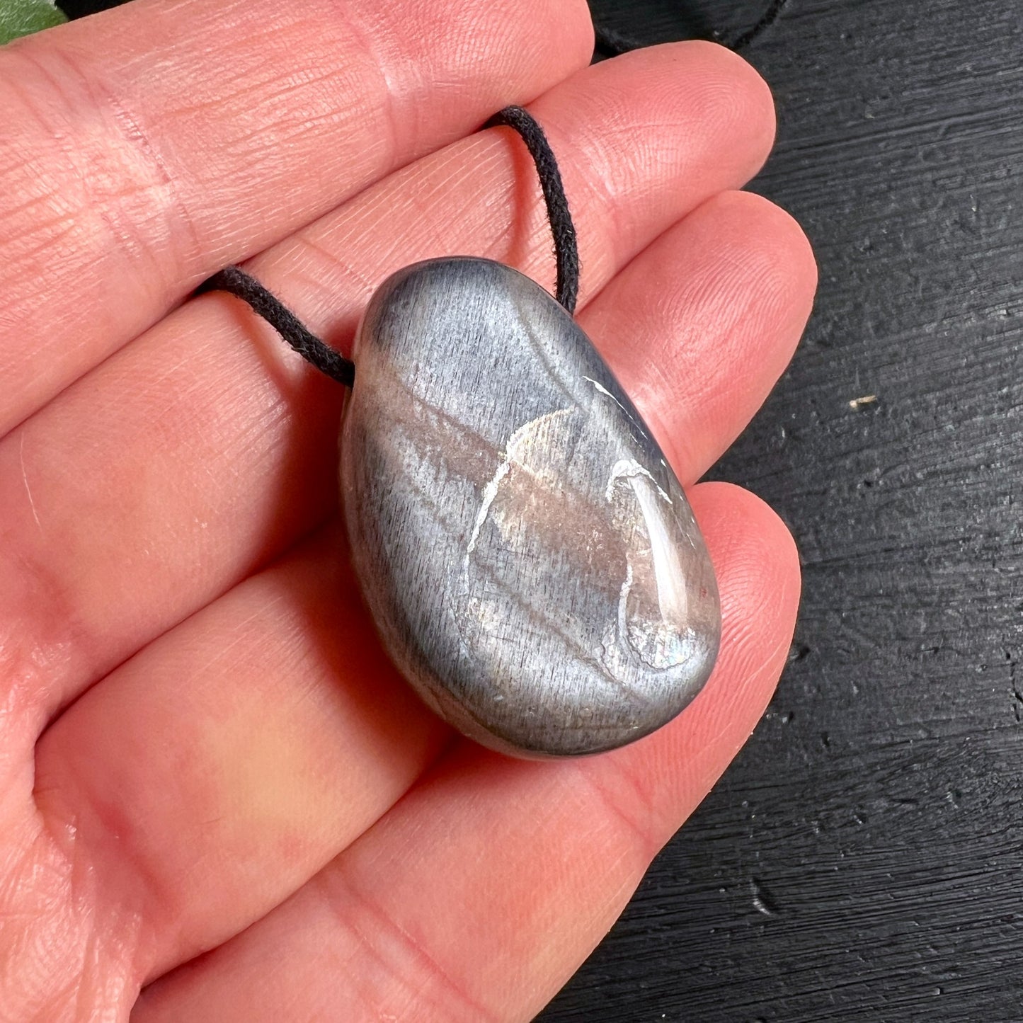Grauer Mondstein Anhänger tropfenförmig 30mm mit schwarzer Kordel in Hand | Happy Minerals