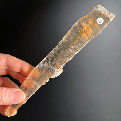 Selenit Kristallstab transparent-orange gestreift in Hand gehalten | Happy Minerals