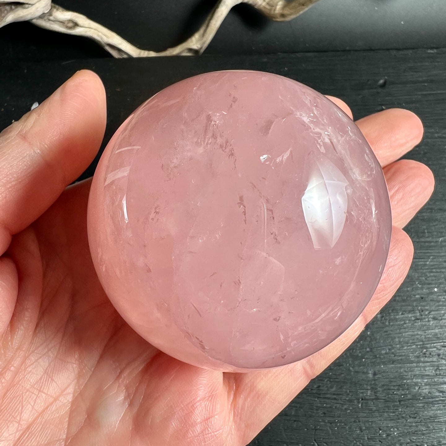 Rosa Rosenquarz Kugel in Hand gehalten, polierte Oberfläche mit natürlichen Einschlüssen | Happy Minerals