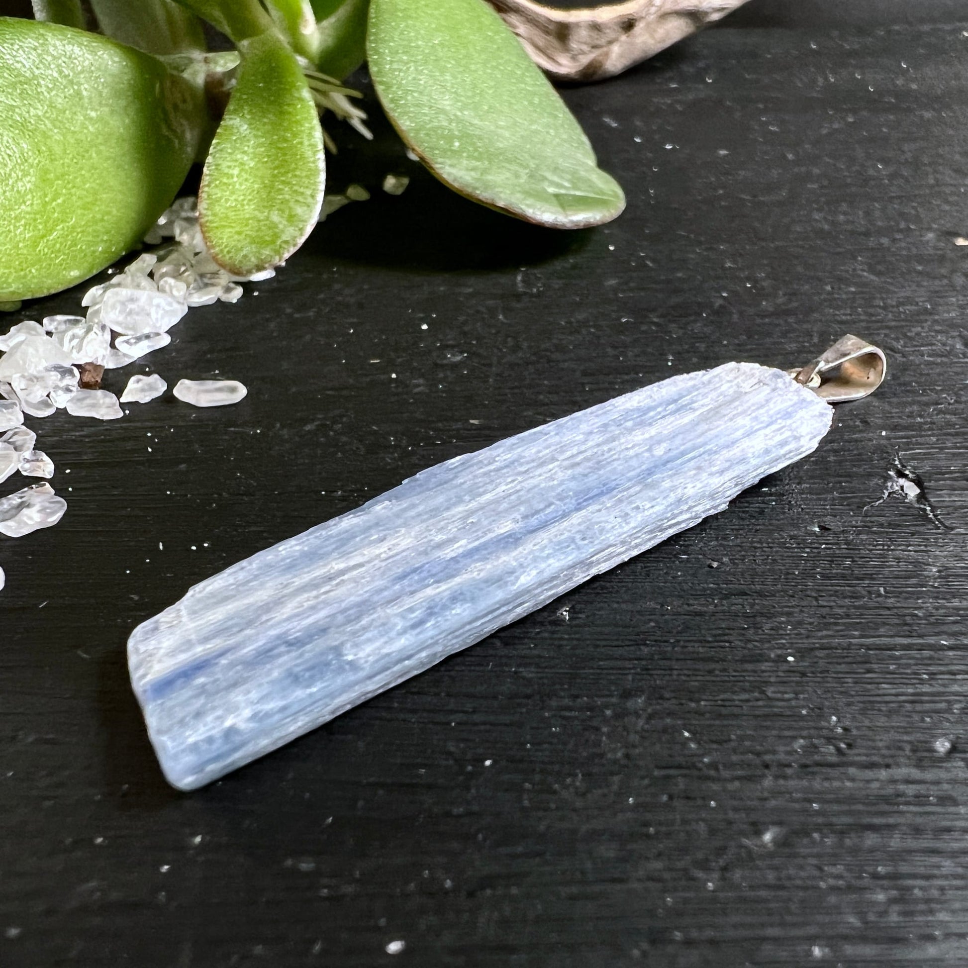 Blauer Kyanit Rohstein Anhänger länglich mit Silberöse auf dunklem Holz | Happy Minerals