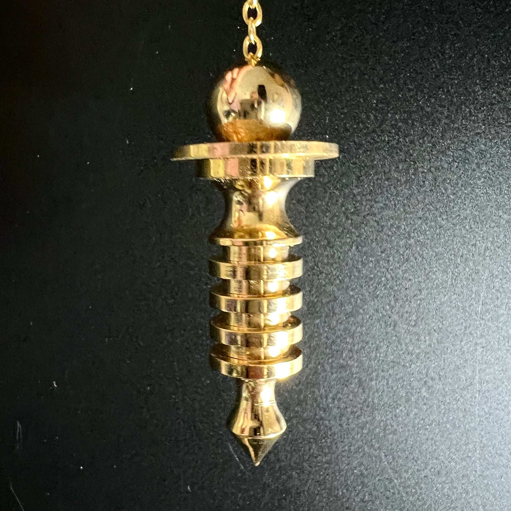 Isis Pendel Messing vergoldet | Nahaufnahme Spiralringe | spitze Spitze | schwarzer Hintergrund | Happy Minerals