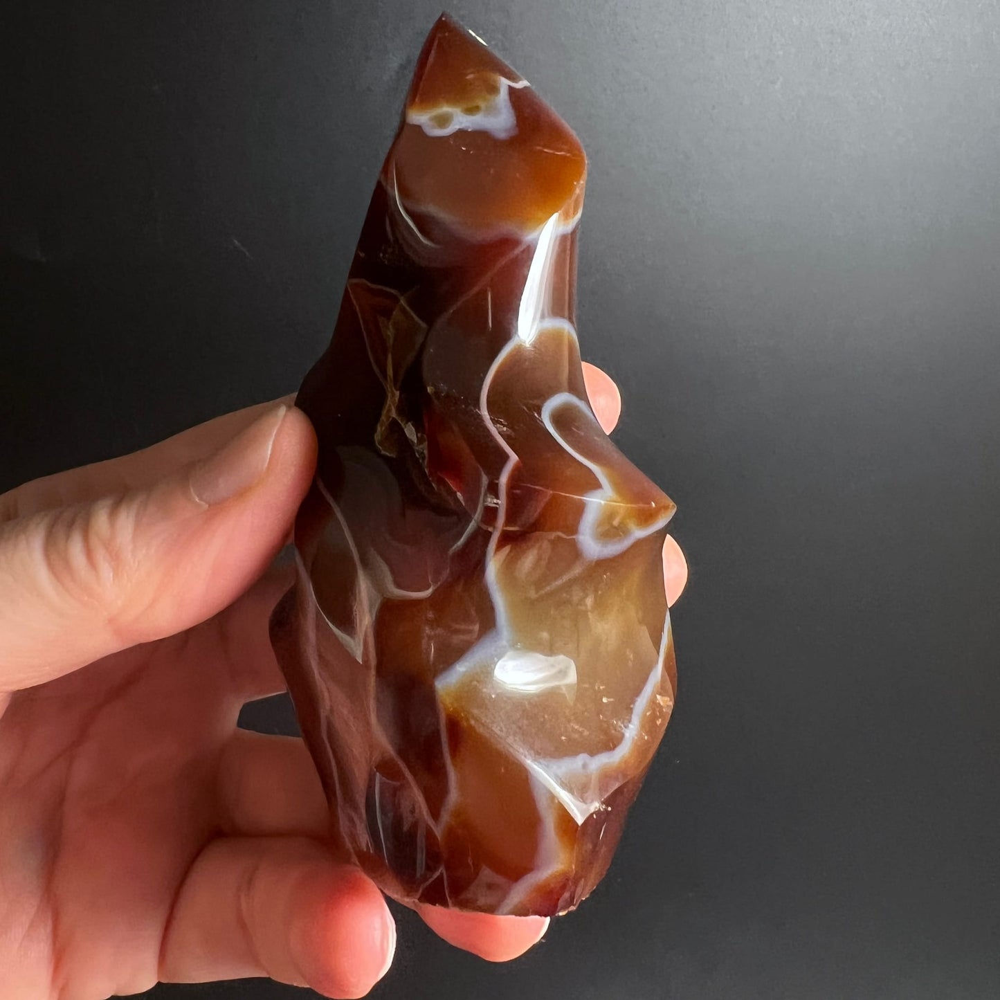Karneol Flamme Handschmeichler | seitlich gehalten | tiefes Rotbraun | schimmernde Oberfläche | Happy Minerals