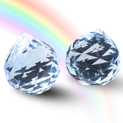 Zwei facettierte klare Kristallkugeln 30mm mit vielflaechigem Schliff, dahinter ein Regenbogen-Lichtspektrum | Happy Minerals
