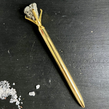 Goldener Kugelschreiber mit rohem Pyrit-Kristall in krallenartiger Fassung auf schwarzem Untergrund | Happy Minerals