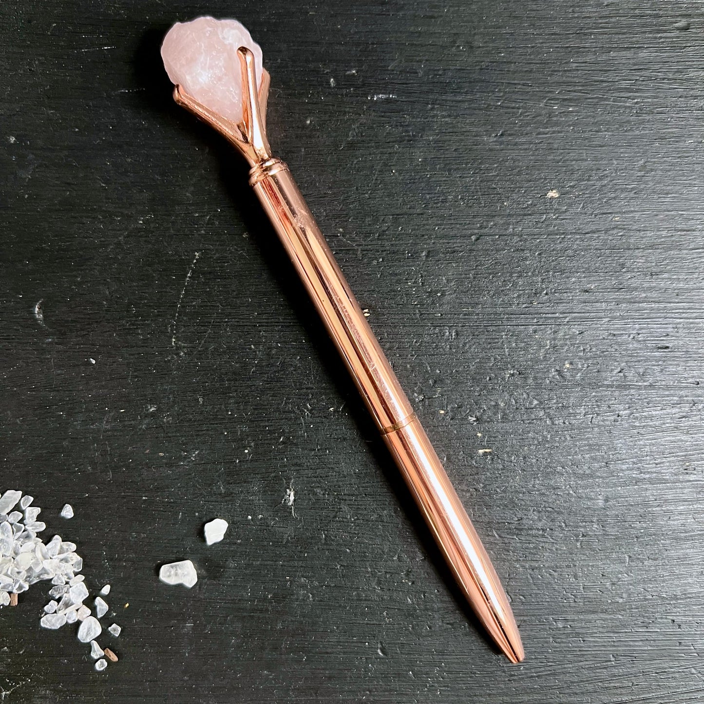 Kugelschreiber roségold mit rohem Rosenquarz-Kristall in Krallenfassung auf schwarzem Holzuntergrund | Happy Minerals