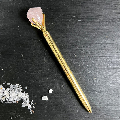 Goldener Kugelschreiber mit rohem rosa Rosenquarz-Kristall in Krallenfassung auf schwarzem Holz | Happy Minerals